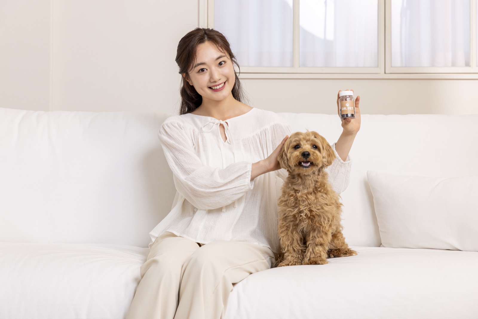 소파에서 반려견과 함께 영양제 통을 들고 있는 보호자